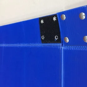 Close-up of blue PP corrugated box panels with metal fasteners and a black patch.
