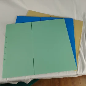 Green folded PP corrugated box sample laid flat over blue and tan panels.